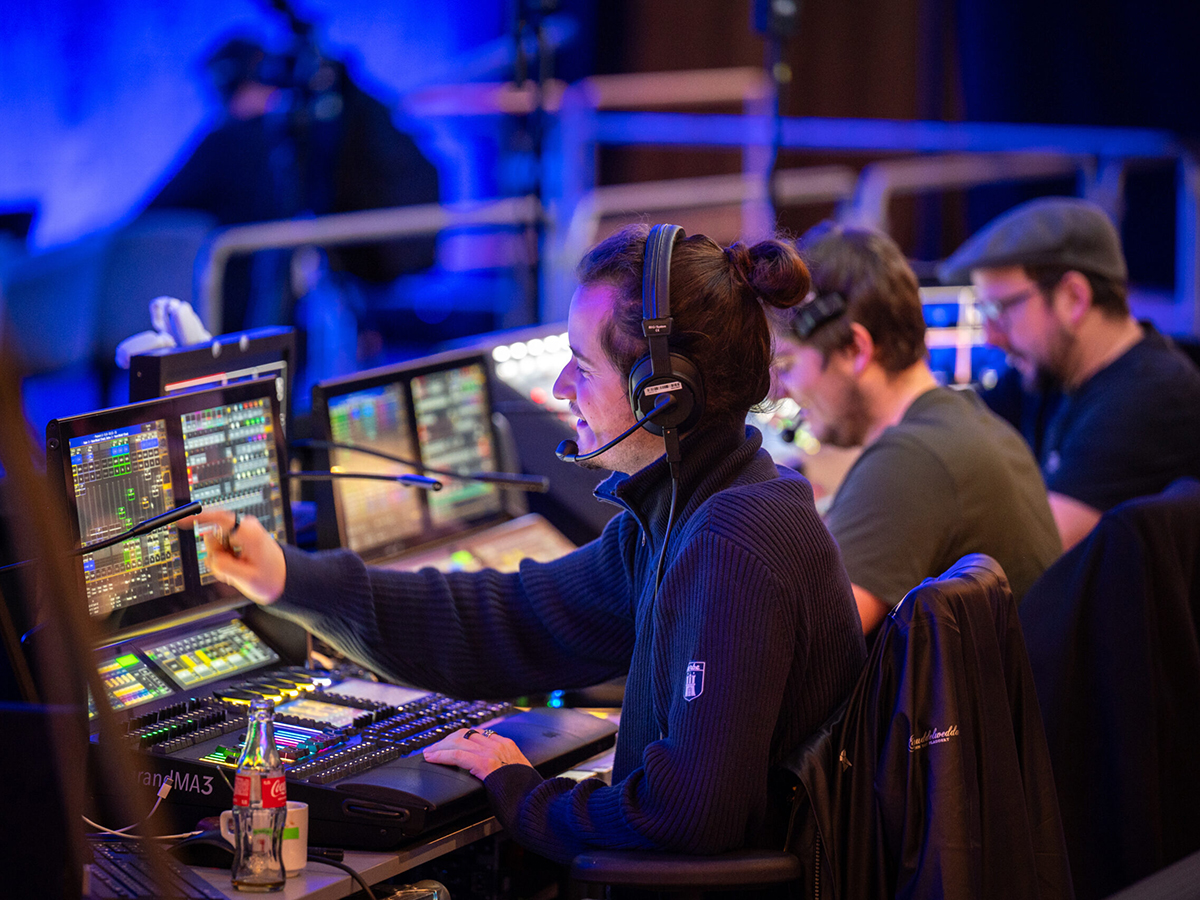 Tech crew at lighting and production control desks during the show rehearsal.